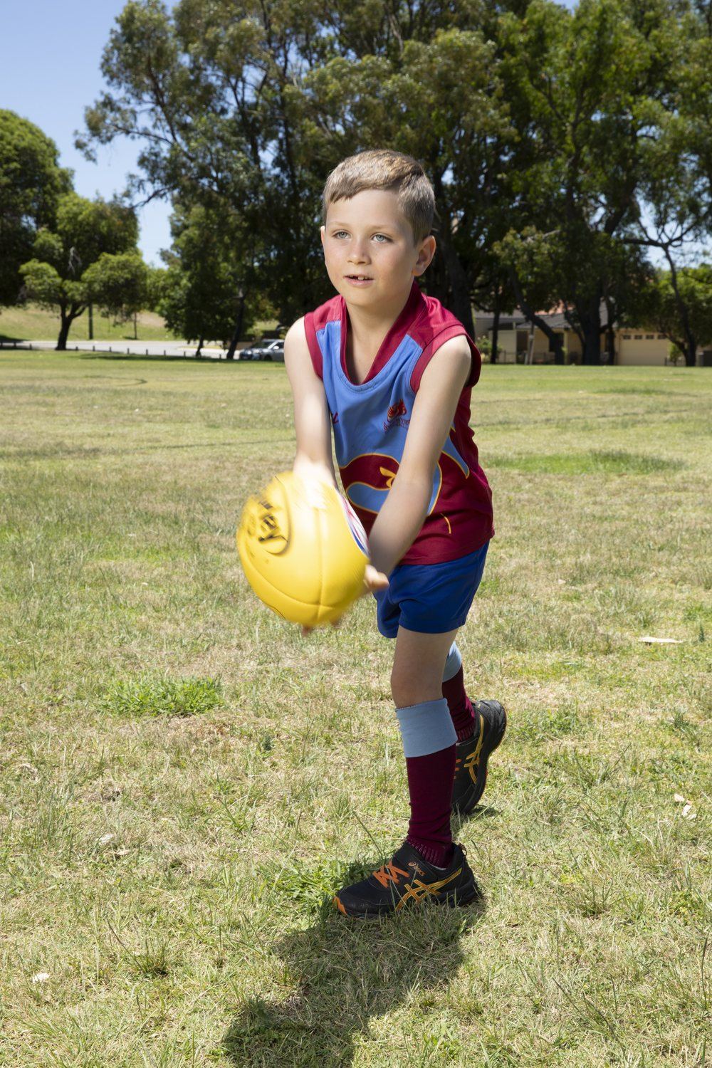 A young Auskick-age player about to handball a football