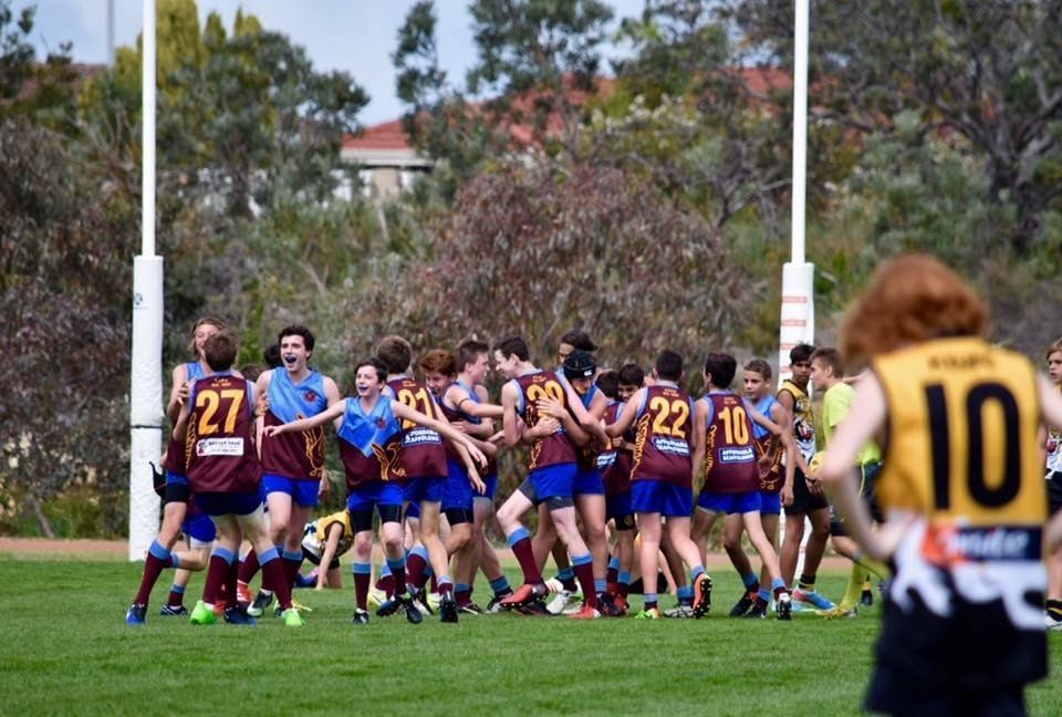Junior players celebrating together in front of the goalposts